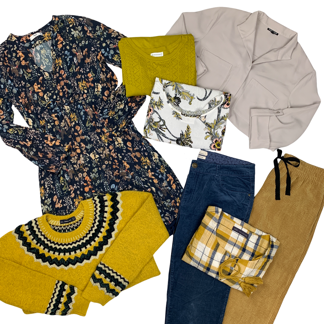 A variety of women's clothing items laid out, including floral tops, a beige cardigan, a yellow sweater, and plaid pants.